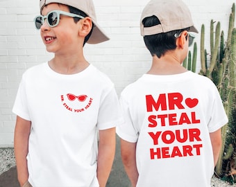May include: White t-shirt with red text that says "MR. STEAL YOUR HEART" on the back. The front of the shirt has a red pair of sunglasses with the text "MR. STEAL YOUR HEART" around the sunglasses.