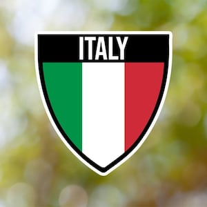 Könnte beinhalten: Ein schildförmiger Aufkleber mit den Farben der italienischen Flagge: grün, weiß und rot. Das Wort "ITALIEN" ist oben auf dem Aufkleber in Schwarz gedruckt.