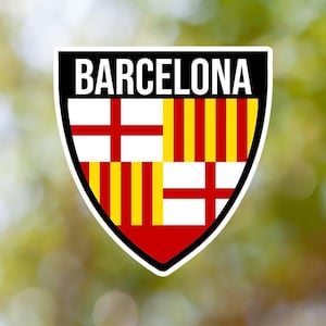 Puede incluir: Un logotipo en forma de escudo negro y blanco con la palabra "BARCELONA" en letras blancas. El escudo está dividido en cuatro secciones con rayas rojas, amarillas y blancas.