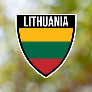 Puede incluir: Una pegatina blanca en forma de escudo con la palabra "LITHUANIA" en texto negro en la parte superior. El escudo está dividido en tres franjas horizontales: amarilla, verde y roja.