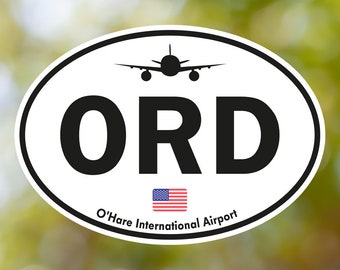 May include: Oval sticker with a white background and black border. The sticker features the letters "ORD" in bold black font, a silhouette of an airplane, and the text "O'Hare International Airport" with a small American flag.