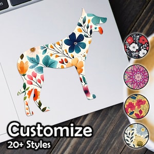 May include: A floral patterned dog silhouette sticker with the text "Customize 20+ Styles". The sticker is on a white laptop with a wooden surface underneath. There are several round stickers with different floral patterns around the main sticker.