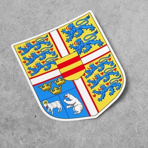 Puede incluir: Un escudo amarillo, blanco y azul con una franja roja y amarilla, tres coronas doradas, un carnero blanco y un oso polar blanco. El escudo está rodeado por un borde azul con corazones rojos y leones azules.