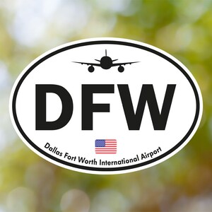 Può includere: Adesivo ovale bianco con testo nero "DFW" e le parole "Dallas Fort Worth International Airport". Una piccola bandiera americana si trova sotto il testo. Una silhouette nera di un aereo si trova sopra il testo.