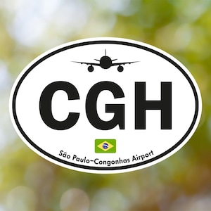 Puede incluir: Adhesivo ovalado con fondo blanco y borde negro. El adhesivo presenta las letras "CGH" en negrita negra, una silueta de avión y el texto "São Paulo-Congonhas Airport". También hay una bandera brasileña.