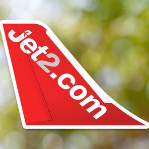 Op de afbeelding: Een rode vliegtuigstaart met een witte omtrek en de tekst "Jet2.com" in wit.