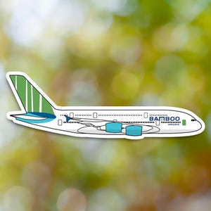 May include: A white aeroplane with green and blue accents. The aeroplane has the words "Bamboo Airways" on the side.