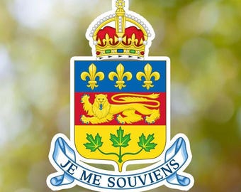 May include: A sticker featuring the coat of arms of Quebec with a crown at the top, a blue section with three gold fleur-de-lis, a red section with a gold lion, a yellow section with three green maple leaves, and a banner reading JE ME SOUVIENS.