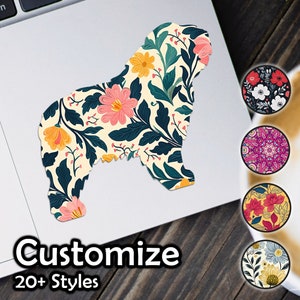 Könnte beinhalten: Ein Aufkleber mit der Silhouette eines Hundes mit einem floralen Muster in Rosa-, Gelb- und Grüntönen. Der Aufkleber befindet sich auf einem Laptop mit einer Holzoberfläche darunter. Das Bild zeigt auch mehrere andere Aufkleber mit verschiedenen floralen Mustern.