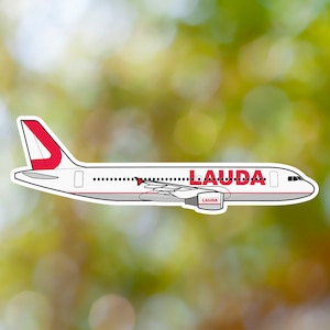 May include: A white aeroplane with red accents and the word "LAUDA" printed on the side. The aeroplane has a red tail fin with a white letter "J" on it.