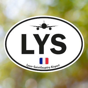 May include: Oval sticker with a black border, featuring the letters "LYS" in bold black font, a silhouette of an airplane, and the French flag. The text "Lyon-Saint-Exupéry Airport" is below the flag.