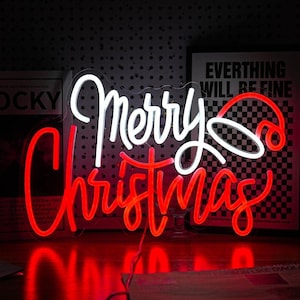 Può includere: Un'insegna al neon con la scritta "Merry Christmas" in corsivo. La parola "Merry" è bianca e "Christmas" è rossa. Un cappello di Babbo Natale rosso è incluso nel design. L'insegna è illuminata, ideale per le festività.