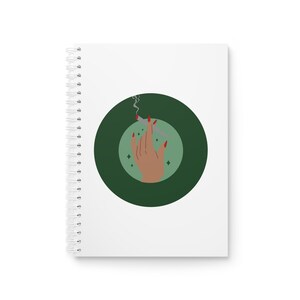 May include: A white notebook with a green circle containing a hand holding a lit cigarette with smoke coming from it. The hand has red nail polish and the background of the circle is a light green.