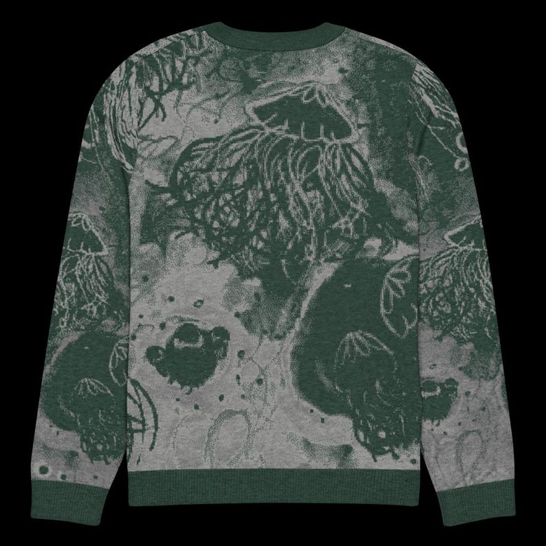 K&ouml;nnte beinhalten: Gr&uuml;ner und grauer Rundhals-Pullover mit Quallen-Design. Der Pullover hat einen dunkelgr&uuml;nen Kragen, B&uuml;ndchen und Saum. Das Quallenmuster ist in dunklerem Gr&uuml;n mit grauem Hintergrund.