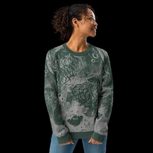 K&ouml;nnte beinhalten: Ein gr&uuml;nes und graues Sweatshirt mit einem Quallen-Design. Der lang&auml;rmlige Pullover hat einen Rundhalsausschnitt und gerippte B&uuml;ndchen und Saum. Das Quallenmuster ist eine Mischung aus Dunkelgr&uuml;n und Grau und erzeugt einen strukturierten, k&uuml;nstlerischen Look. Der Hintergrund ist schwarz.