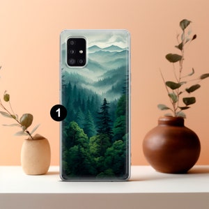 May include: A clear phone case featuring a landscape painting of a forest and mountains. The artwork depicts a lush green forest with tall trees and rolling hills, with a misty atmosphere. The case is on a white surface with decorative vases.