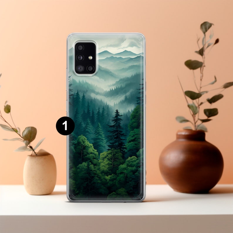 May include: A clear phone case featuring a landscape painting of a forest and mountains. The artwork depicts a lush green forest with tall trees and rolling hills, with a misty atmosphere. The case is on a white surface with decorative vases.