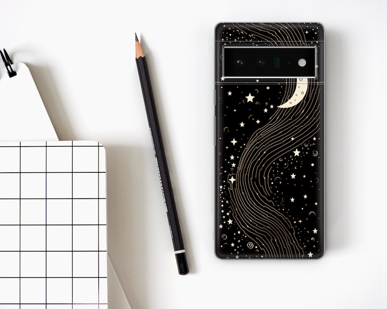 Puede incluir: Carcasa de tel&eacute;fono negra con un dise&ntilde;o de media luna y estrellas doradas sobre un fondo negro.