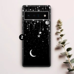 Puede incluir: Carcasa de tel&eacute;fono negra con un dise&ntilde;o de luna creciente y estrellas. La carcasa tiene una parte posterior transparente y un borde negro.
