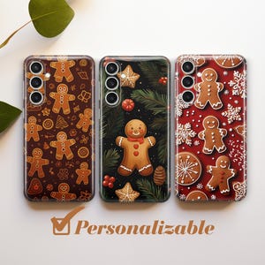 Puede incluir: Tres fundas para teléfono con un tema navideño de pan de jengibre. Las fundas tienen todos diseños diferentes, pero todas presentan hombres y mujeres de pan de jengibre, copos de nieve y otras decoraciones navideñas. Las fundas son todas negras y tienen un fondo blanco.