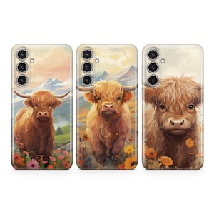 May include: Three phone cases with a Highland Cow design. Each case features a different Highland Cow with a brown and white coat, standing in a field of flowers. The background is a blurred image of a mountain range.