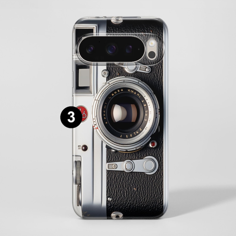 Pu&ograve; includere: Custodia trasparente per telefono con un design di fotocamera vintage. La custodia ha una texture nera simile alla pelle sul lato destro, con dettagli argentati e neri. L'obiettivo della fotocamera &egrave; prominente.