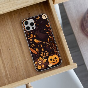 May include: A black phone case with a Halloween theme. The case features a black cat, a pumpkin, and other Halloween-themed imagery. The case is designed for a phone with a triple camera lens.