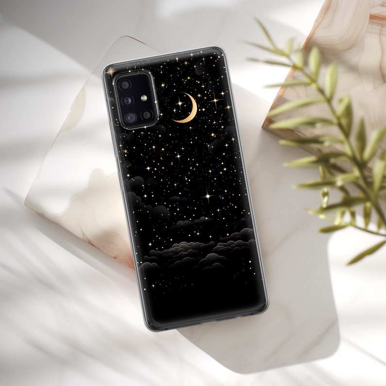 May include: A black phone case with a gold crescent moon and stars design. The case is made of clear plastic and has a raised edge to protect the screen.