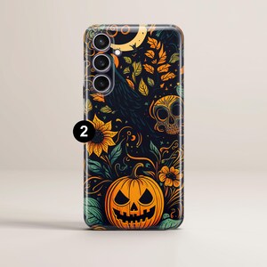 May include: A black phone case with a Halloween-themed design. The design features a jack-o'-lantern, a skull, sunflowers, and a raven. The phone case has a cutout for a triple-lens camera.
