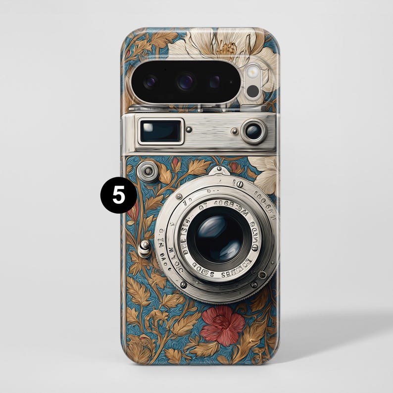 Pu&ograve; includere: Una custodia per telefono con un design a fotocamera vintage. La custodia ha uno sfondo blu con motivi floreali dorati, bianchi e rossi. L'obiettivo e i dettagli della fotocamera sono argentati.