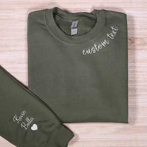 May include: A green sweatshirt with the text "custom text" embroidered on the front and "Kevin Bella" with a heart embroidered on the sleeve.