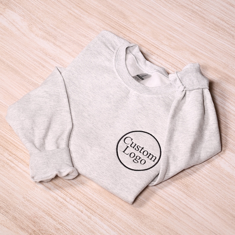 May include: A gray sweatshirt with a black circle and the text "Custom Logo" in white.