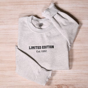 Può includere: Una felpa grigia con la scritta "LIMITED EDITION Est. 1992" stampata sul davanti.