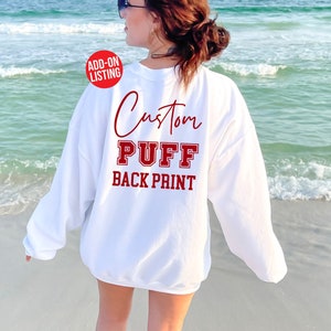 May include: White sweatshirt with the text "Custom Puff Back Print" in red lettering on the back.