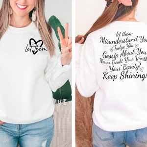 May include: White sweatshirt with the text "Let them Misunderstand You Judge You Gossip About You Never Doubt Your Worth! Your Beauty Keep Shining!" printed on the back. The front of the sweatshirt has a heart with the text "Let them" inside.
