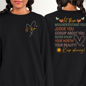 May include: Black sweatshirt with a motivational quote on the back that reads "Let them misunderstand you, judge you, gossip about you, never doubt your worth! Your beauty! Keep shining!" and a small heart on the front with the text "Let them" on the front.