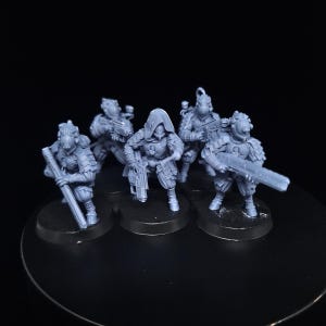 Peut inclure: Cinq figurines miniatures en plastique gris de personnages humanoïdes portant une armure futuriste et tenant des armes. Les figurines sont debout sur des socles circulaires noirs.