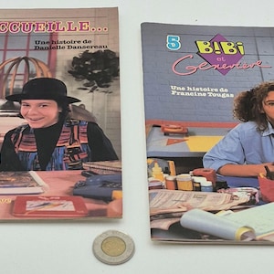 May include: Two vintage French children's books, "Bibi et Genevieve," are shown. The covers feature illustrations of children and puppets. One book is titled "J'accueille," and the other is "Le Ménage." A Canadian two-dollar coin is in the foreground.
