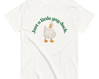 Könnte beinhalten: Weißes T-Shirt mit grünem Text, der "Just a little gay duck" lautet. Ein Cartoon-Ente mit weißem Körper und orangefarbenem Schnabel und Füßen ist mittig auf dem Shirt platziert.