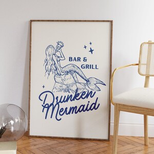 May include: A framed print with a blue illustration of a mermaid holding a seashell. The text "Bar & Grill" and "Drunken Mermaid" are below the illustration.