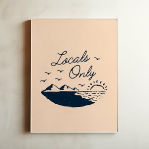 May include: A framed print with a peach background and black text that reads "Locals Only". The print features a stylized illustration of a mountain range, a sun, and birds flying over a body of water.