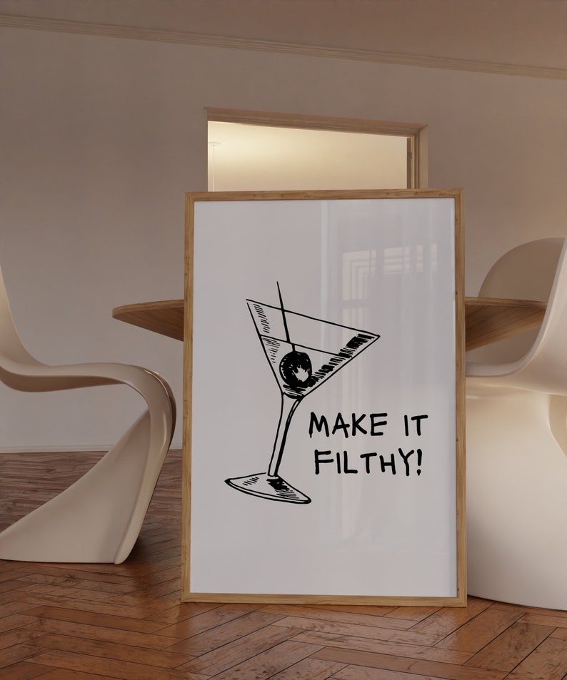 May include: A white framed poster with a black and white illustration of a martini glass with an olive. The text "MAKE IT FILTHY!" is below the illustration.