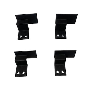 Puede incluir: Cuatro soportes de esquina de metal negro con dos agujeros cada uno. Los soportes tienen forma de L y tienen una superficie plana en la parte superior.