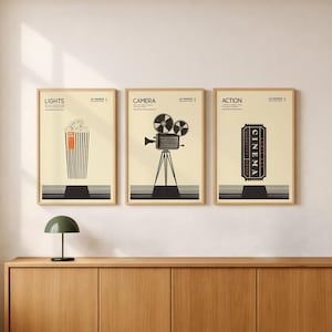 May include: Three framed wall art prints with light cream backgrounds and black line art. The first shows a popcorn bucket labelled LIGHTS, the second a film camera labelled CAMERA, and the third a cinema ticket labelled ACTION with black striped bases.