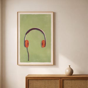 May include: A framed art print featuring a stylized illustration of orange headphones against a green background. The headphones have a dark purple headband and a connecting cord. The artwork is in a wooden frame.
