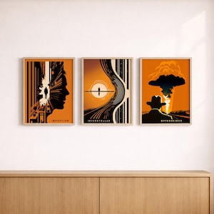 May include: A set of three rectangular wall art prints with orange, black, and cream color palettes. The left print shows a silhouette profile and the text INCEPTION. The center print features a sun and lines with the text INTERSTELLAR. The right print displays a mushroom cloud and the text OPPENHEIMER.