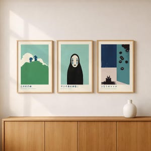 three framed artworks displayed on a wooden cabinet against a white wall.