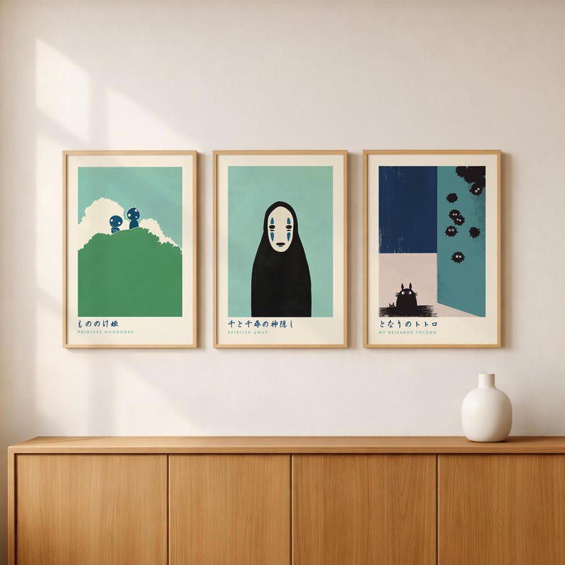three framed artworks displayed on a wooden cabinet against a white wall.