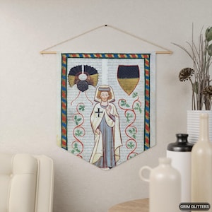 May include: A medieval tapestry featuring a depiction of a person in a white robe with a red cross on the chest. The person is standing in front of a vine with green leaves and a shield with black and gold colors. The tapestry has a red, yellow, and blue border.