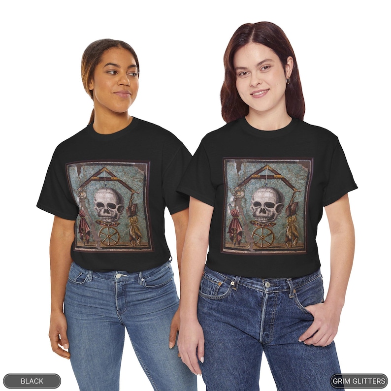May include: Two people wearing black t-shirts with a graphic print of a skull in a frame. The skull is surrounded by figures and a wheel. The text "GRIM GLITTERS" is printed on the bottom right corner of the image.